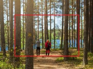 Esimerkkikuva luontokohteesta, jossa kaksi ihmistä kävelee metsäpolulla. Kuvasta on rajattu keskiosa punaisella osoittamaan, että koko kuva ei välttämättä aina näy.