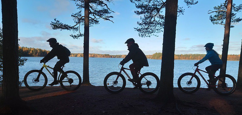 Suunta luontoon hanke kolme pyöräilijää taustalla järvimaisema