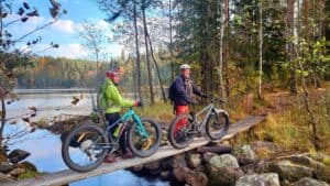 Suunta luontoon hanke kaksi pyöräilijää ylittämässä puroa metsässä