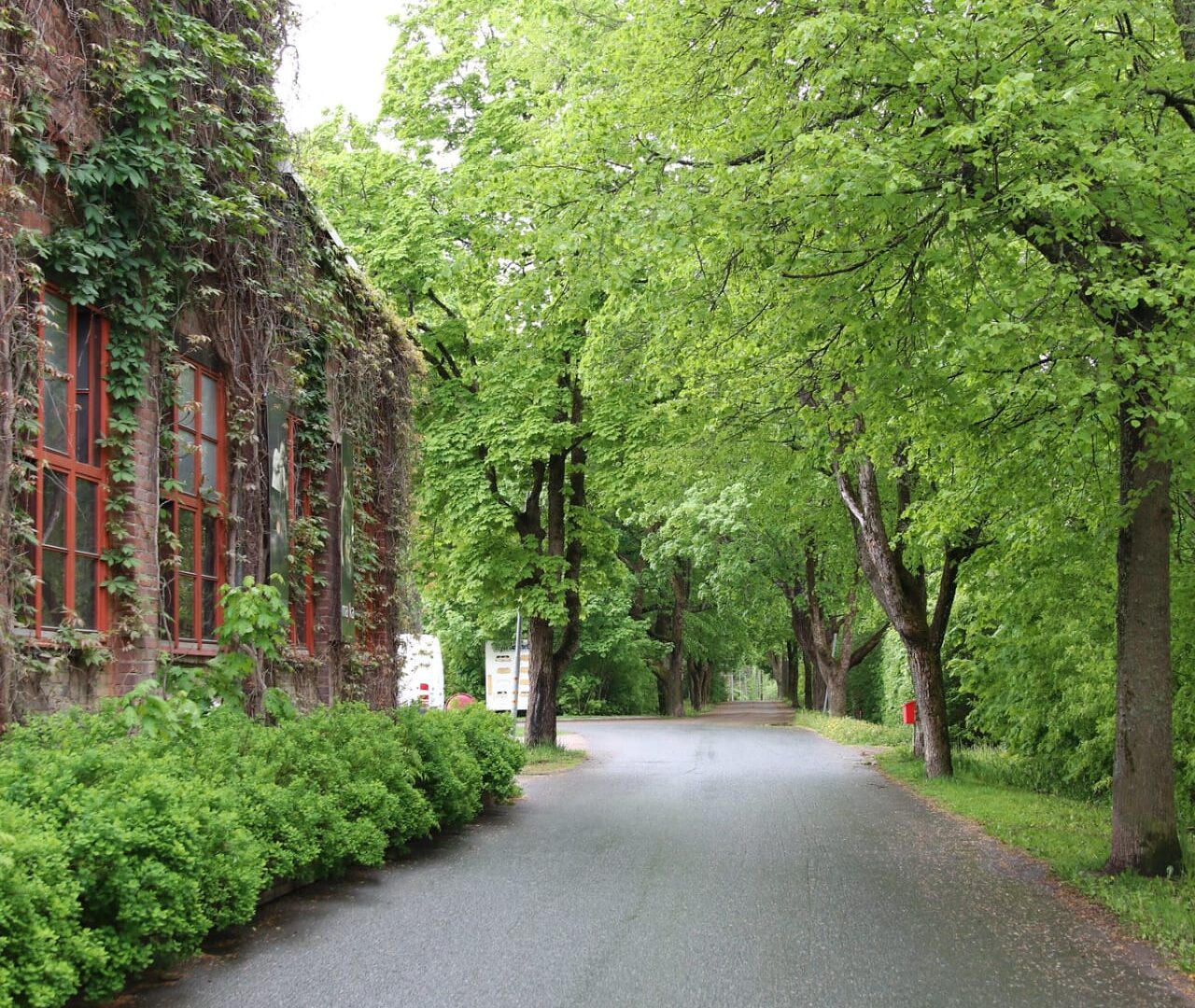 Punatiilinen rakennus, jota ympäröi vihreät puut ja kasvillisuus.