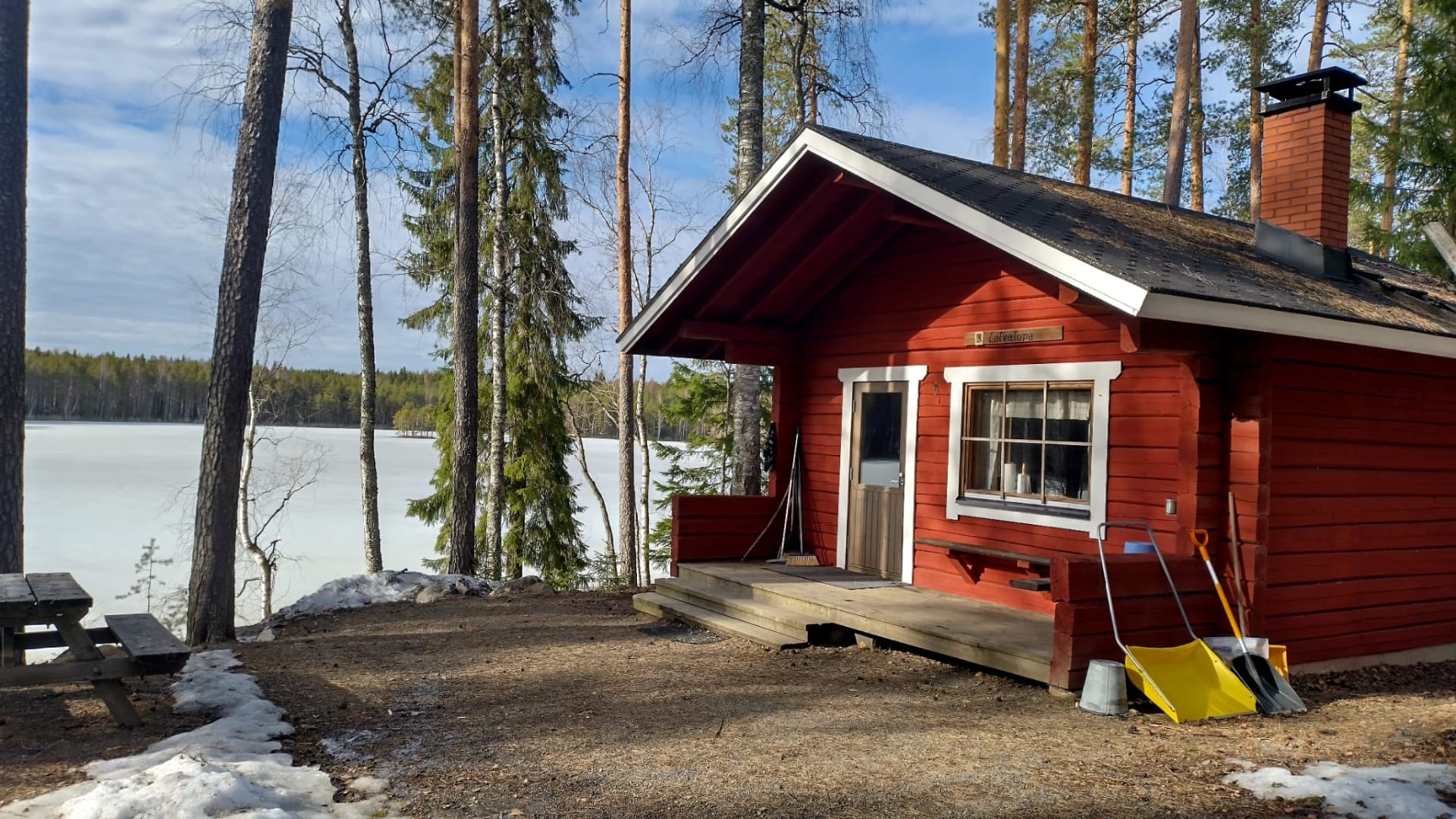 Neljä ihmistä kävelemässä suomaisemassa pitkospuilla, takana korkeita puita, joiden välistä pilkistää auringonsäteitä.