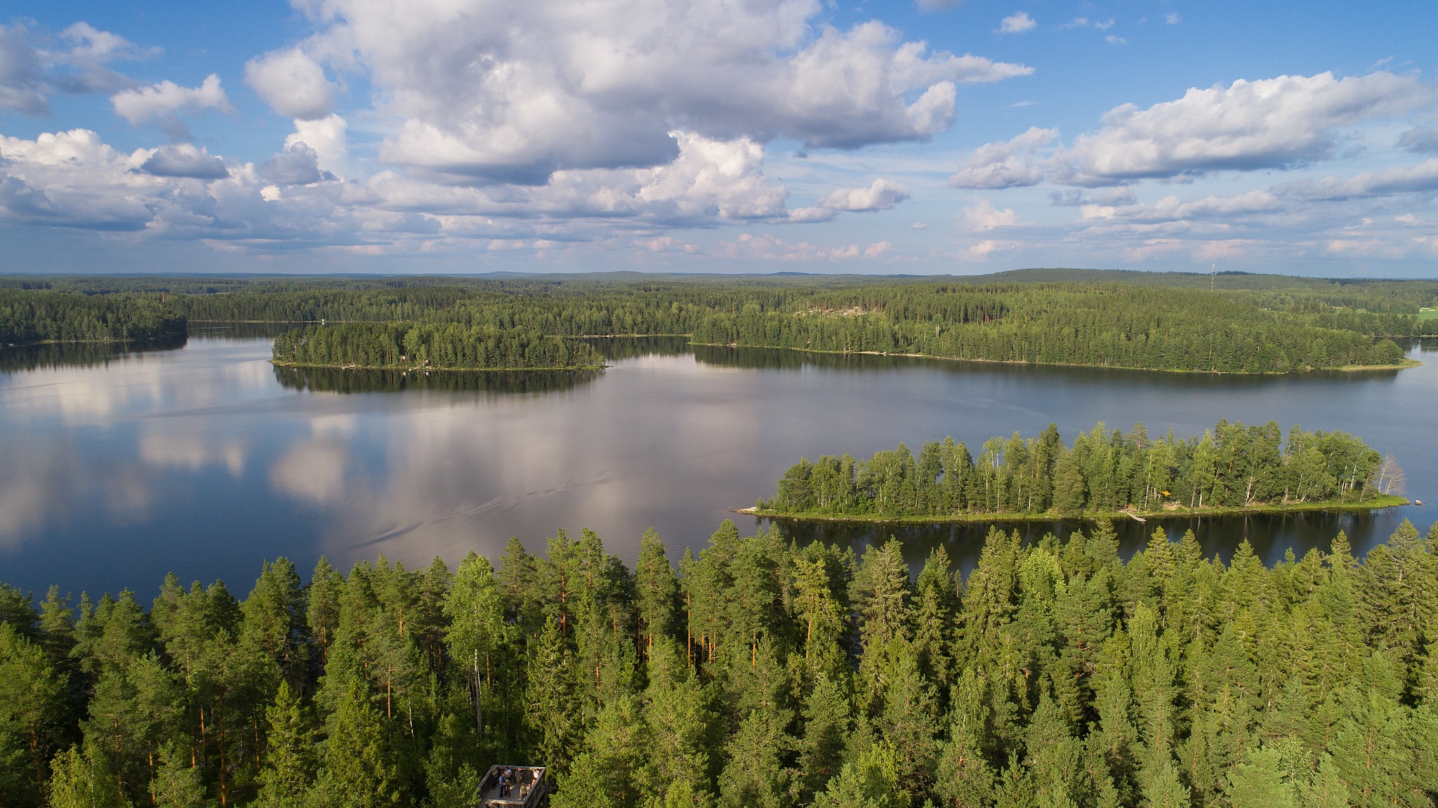 Järvimaisema ylhäältä kuvattuna. Taivaalla on pilviä ja sinistä taivasta.