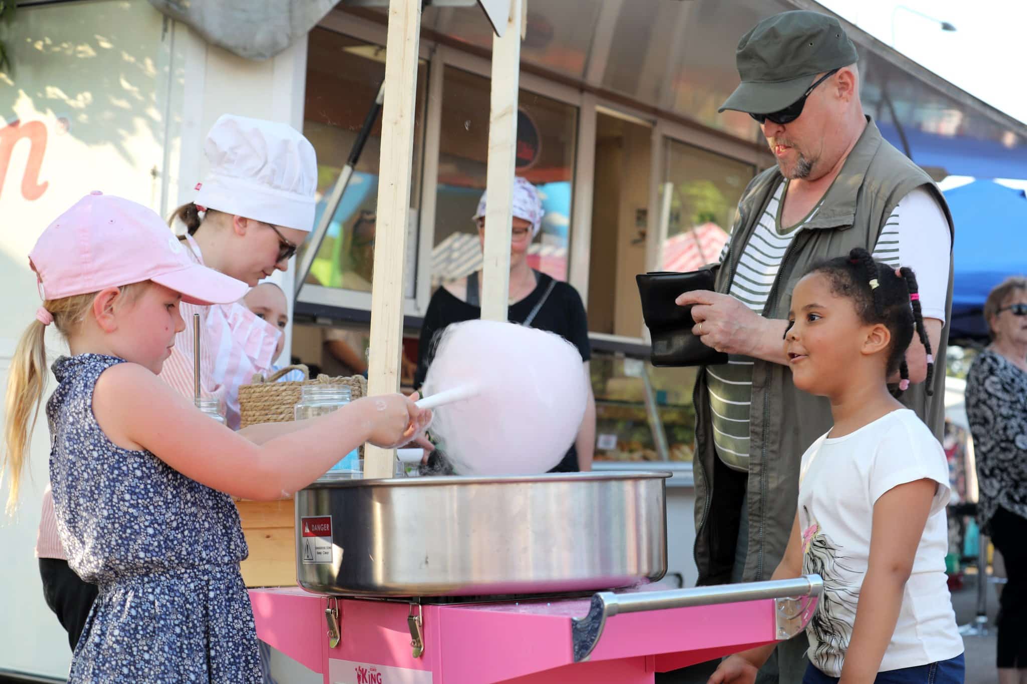 A girl is waiting for her cotton candy in a fair.