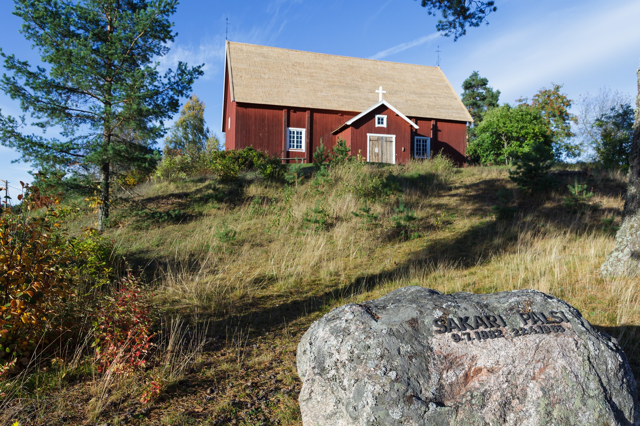 Old red wooden church is on top of a hill.