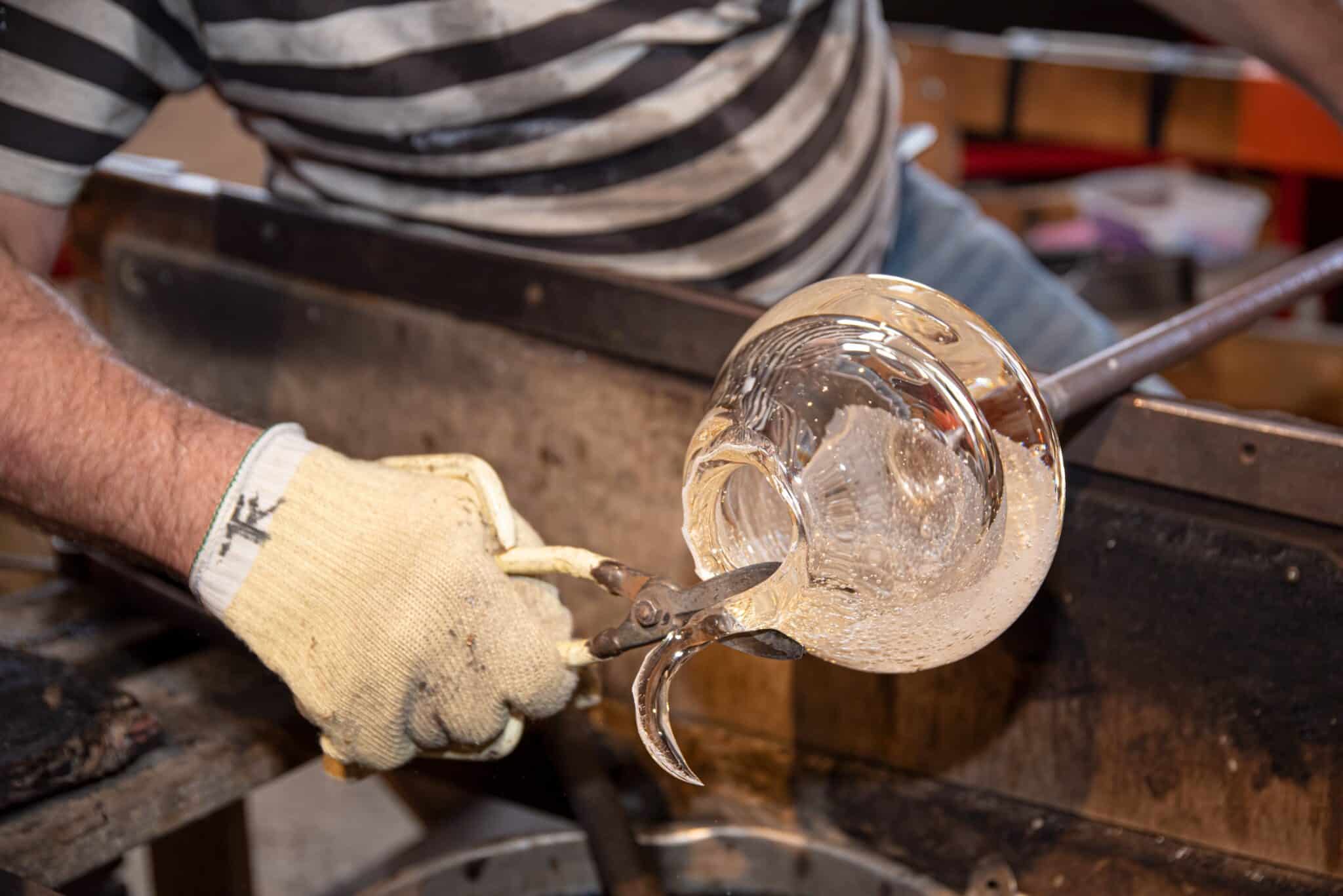 Ein Mann, der Glas in einem Glasstudio formt.