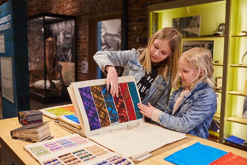 Tytöt selaamassa kuosikansiota Forssan museossa