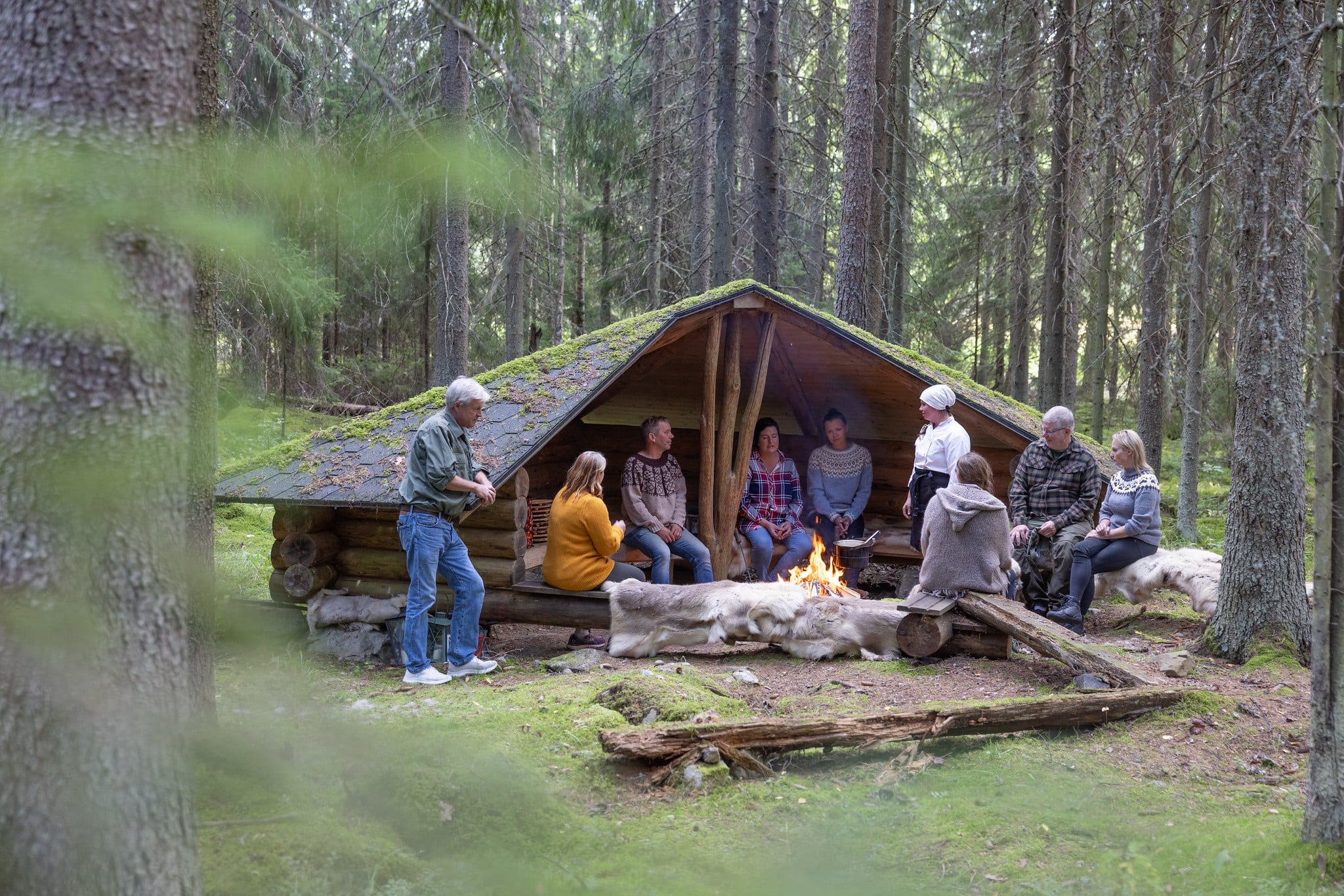 A group of people sitting at a shelter in the forest.