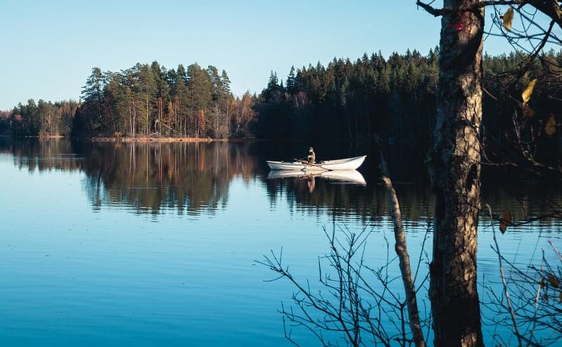 Soutuvene ja soutaja peilityynellä järvellä.