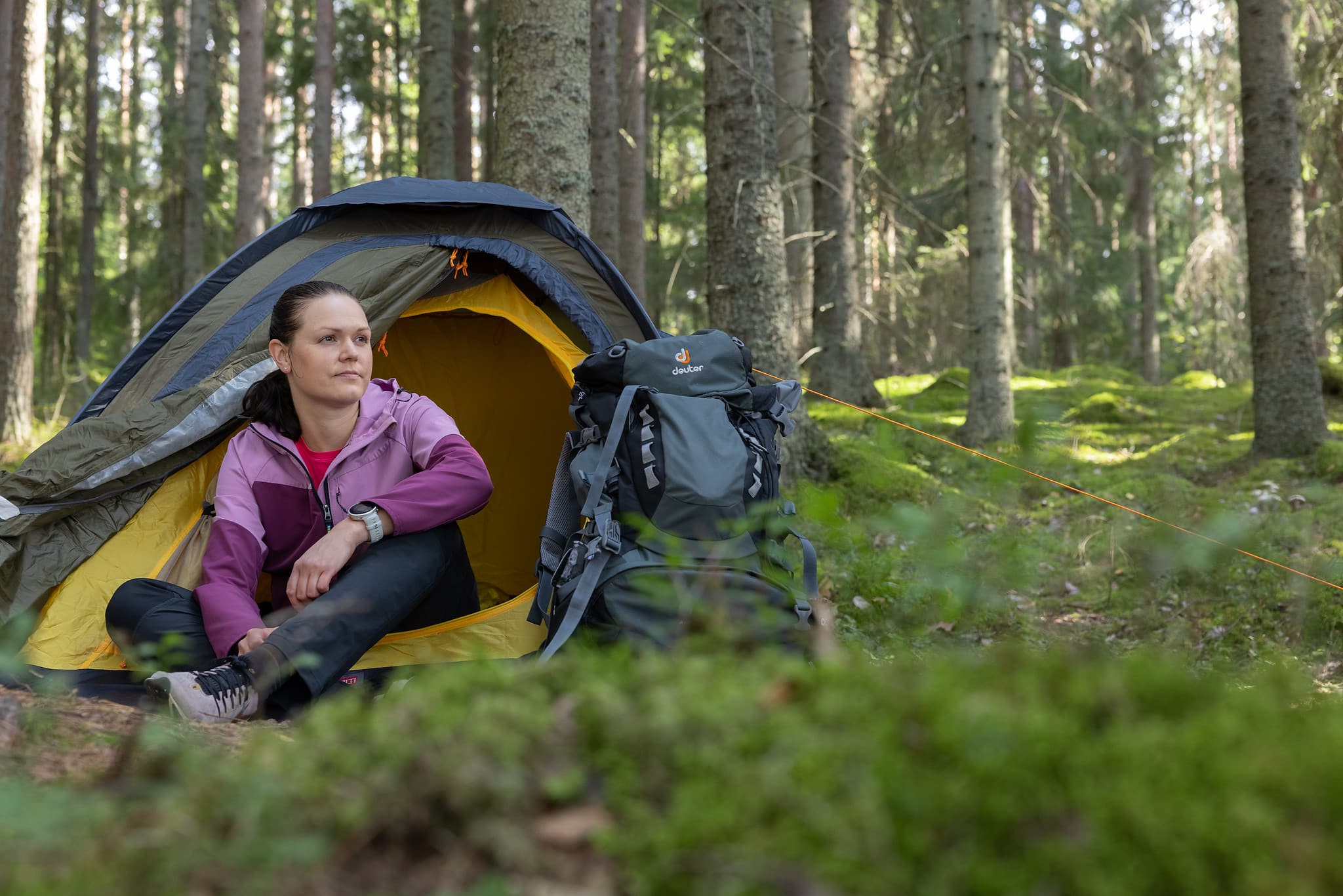 A woman is sitting in her tent in a forest