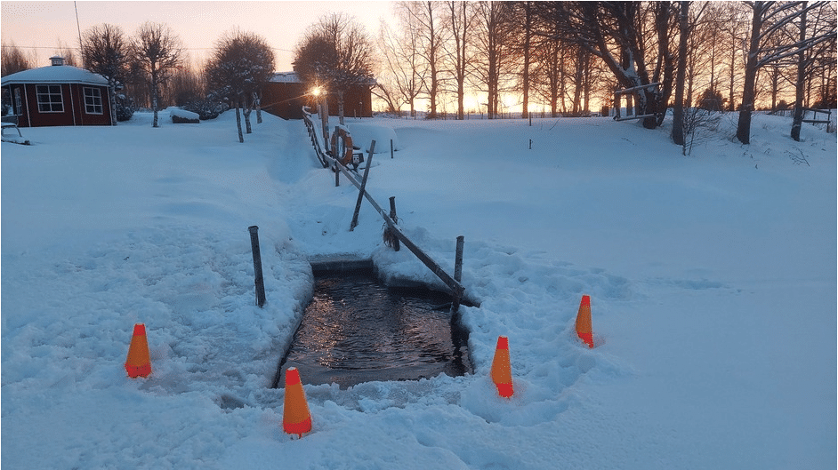 Lumen ympäröimään avantoon johtaa polku ja puiset kaiteet polun toisella puolella.