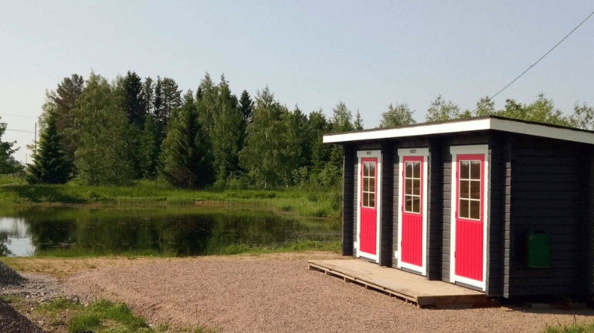 Hiekkaranta ja pukukoppi/käymälä jossa kolme ovea.