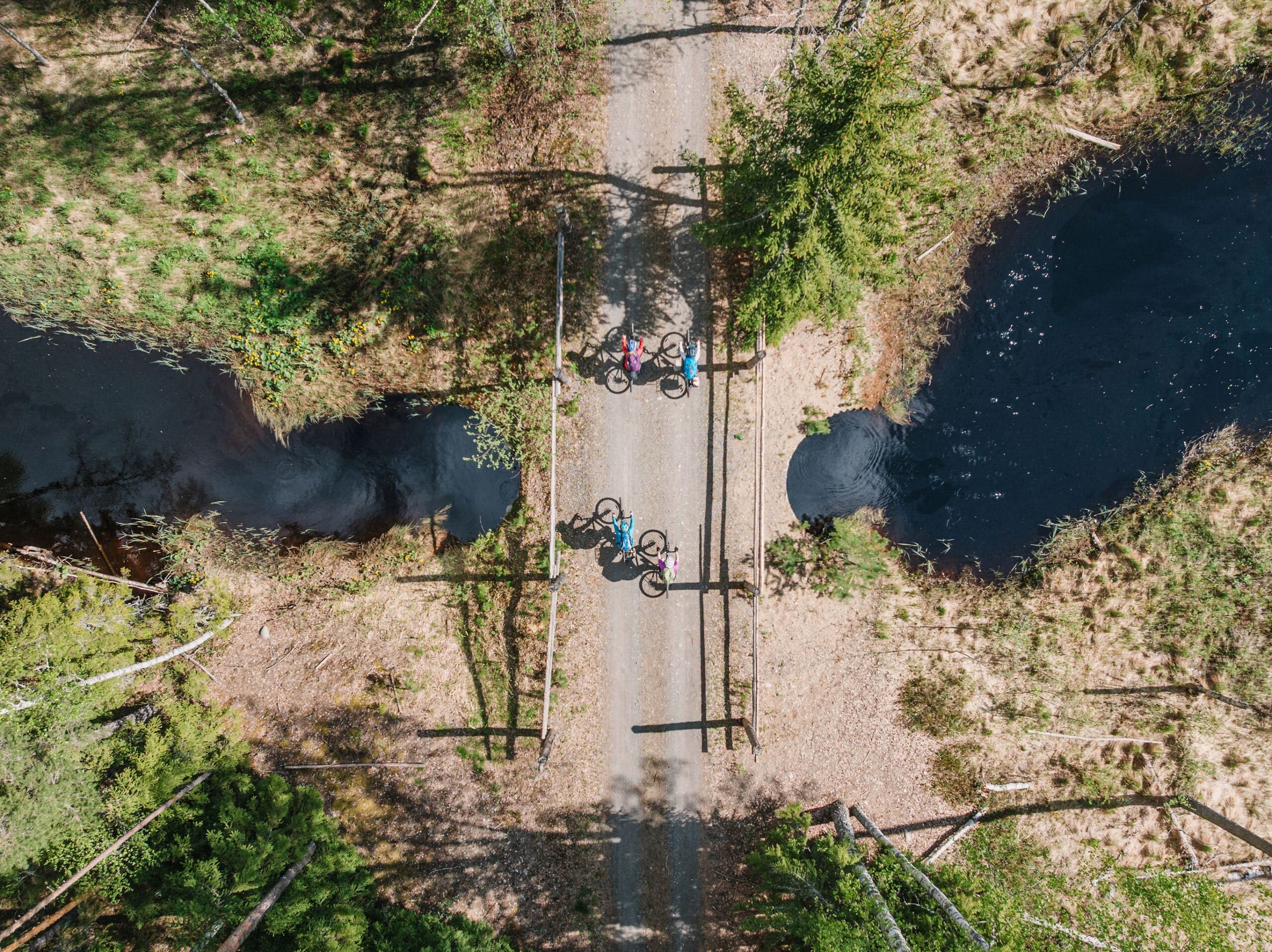 Pyöräilijät pyöräilevät vesistön yli kapealla sillalla.